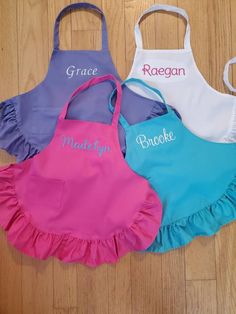 three children's aprons with personalized names on them