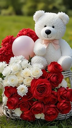 a teddy bear sitting on top of a basket filled with red roses and white flowers