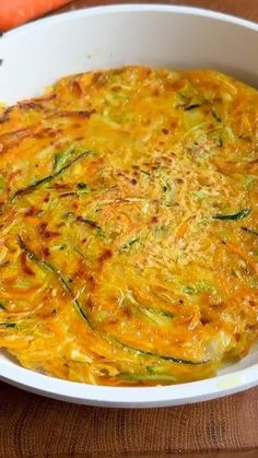 an omelet with zucchini and cheese in a white bowl on a wooden table