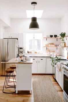 a kitchen with white cabinets and stainless steel appliances, including an island in the middle