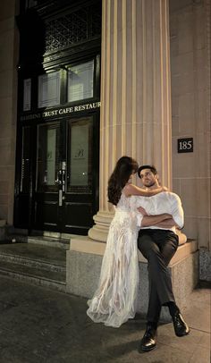 a man and woman sitting on a bench in front of a building