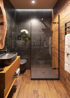 a modern bathroom with wood floors and black walls, along with a walk in shower