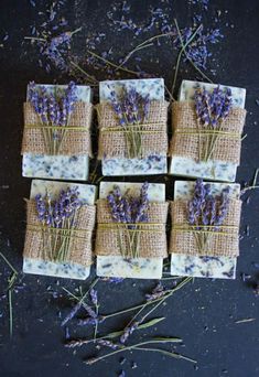 soap bars with lavender flowers tied to them on a black surface next to dried herbs