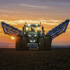 a tractor with lights on driving in the sunset