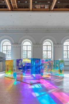 an art gallery with multiple colored glass cubes in the center and windows on either side