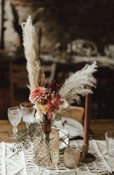 an image of a table setting with flowers and feathers in vases on the table