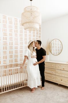 a man and woman standing in front of a crib with a baby's bed