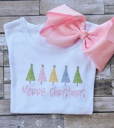 a t - shirt that says merry christmas with trees on it and a pink bow