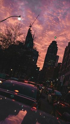 the sky is pink and purple as cars are parked on the street