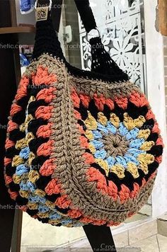 a crocheted bag hanging from a hook on a door way in front of a store