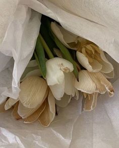 a bouquet of flowers is wrapped in white paper