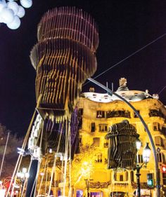 an artistic sculpture is shown in front of a building at night with street lights and traffic