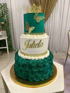 a three tiered cake decorated with green and white icing, gold accents and butterflies