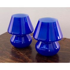 two blue glass vases sitting on top of a wooden table next to each other