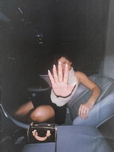 a woman sitting in the back seat of a car holding her hand up