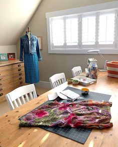 a room with a table, chairs and clothes on it in front of a window