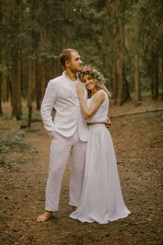 a man and woman are standing in the woods with their arms around each other as they pose for a photo