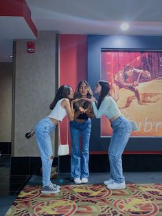 three young women are standing in front of a movie poster and touching their hands with each other