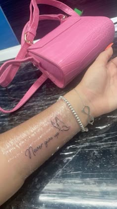 a woman's arm with a tattoo on it and a pink purse behind her