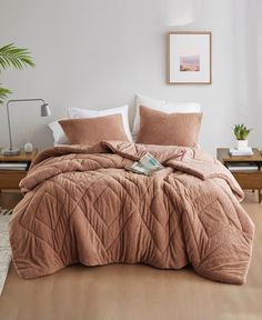 a bedroom with a bed covered in a brown comforter next to a potted plant