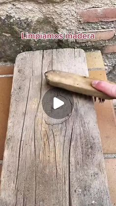 a person holding a knife on top of a wooden table next to a brick wall