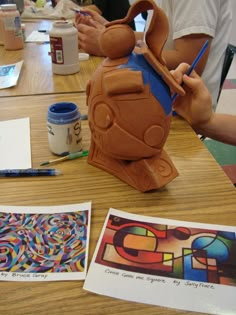 an art project being displayed on a table with people working on the paper and other items