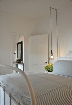 a white bed sitting next to a doorway with a mirror on the wall above it