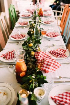 a long table is set with red and white checkered napkins, plates, silverware, and candles