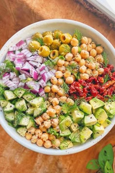 a white bowl filled with lots of different types of food on top of a wooden table