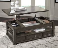 a coffee table with an open drawer underneath it on a rug in front of a window