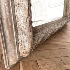 an old mirror is sitting on the floor in front of a white door and wooden floors