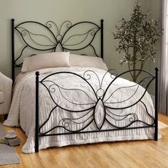 a black metal bed frame with white sheets and pillows on it in a bedroom setting