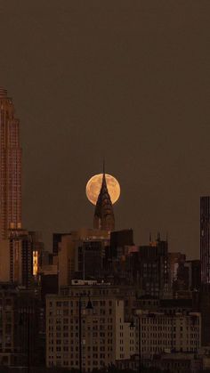 the full moon is seen over a city skyline