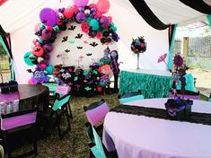 a decorated tent with purple, green and black tables set up for a halloween party