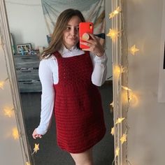 a woman taking a selfie in front of a mirror wearing a red knitted dress