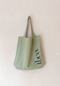 a green tote bag sitting on top of a wooden table next to a white wall