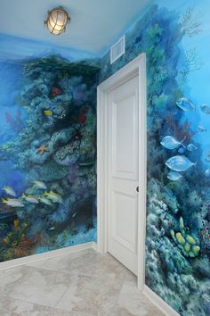 an ocean themed bathroom with fish and corals painted on the wall, along with a white door