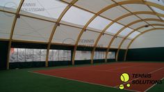 an indoor tennis court with green grass and white walls