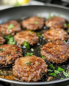 some meat patties are cooking in a skillet