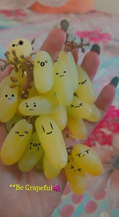 a bunch of yellow grapes with faces drawn on them in the palm of someone's hand