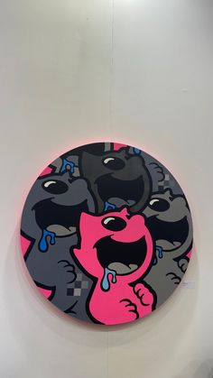 a round painting with pink and black cartoon dogs on it's side hanging from the wall