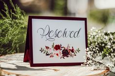 a sign that says reserved sitting on top of a wooden table next to some flowers