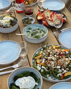 a wooden table topped with plates and bowls filled with different types of food on top of it