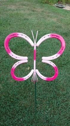 a pink and white butterfly sculpture in the grass