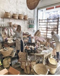 two women working in a pottery shop with baskets on the wall and shelves full of items