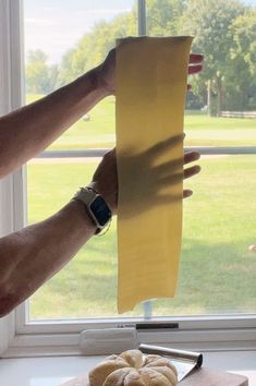 a person holding up a piece of yellow paper next to a doughnut on a cutting board