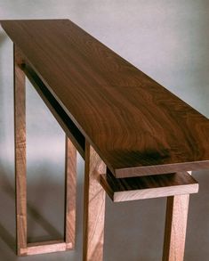 a wooden table sitting on top of a hard wood floor next to a white wall