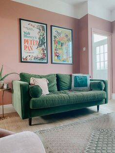 a living room with two posters on the wall and a green couch in front of it