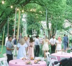 a group of people standing around a table with pink clothed tables in the middle of it