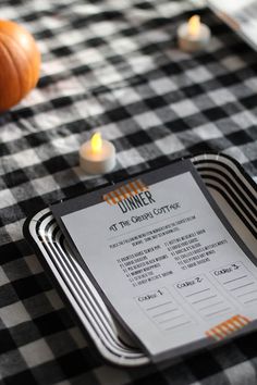 a menu sitting on top of a checkered table cloth next to candles and pumpkins